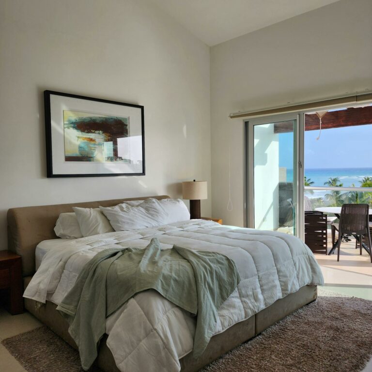 Cozy bedroom in Playa del Carmen with ocean view terrace, modern decor and natural light.