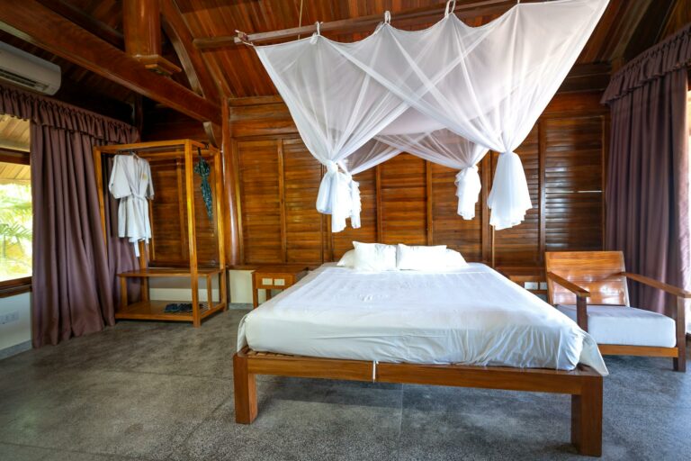 Warm wooden bedroom interior featuring a bed with net canopy and curtains.